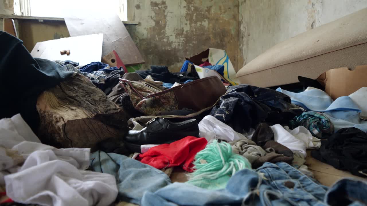 toma cercana en cámara lenta en una casa abandonada en un pueblo solitario lleno de ropa vieja y basura