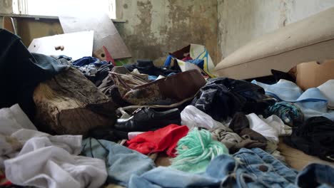 Tiro-En-Cámara-Lenta-En-Una-Casa-Abandonada-En-Un-Pueblo-Solitario-Lleno-De-Ropa-Vieja-Y-Basura