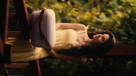 caucasian young girl stares beautifully at outdoors garden in yellow dress, vertical video, makeup and beauty