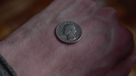 man removes hand covering coin with heads win on back of palam