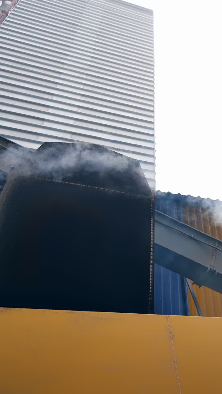 The work of the plant is in progress. Grain processing on the background of the elevator. Vertical video