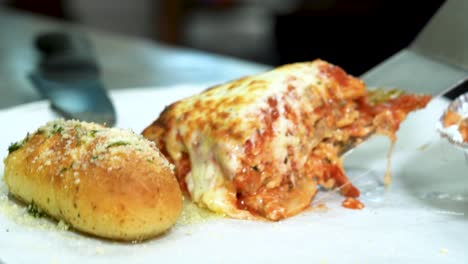 cerca de queso extraer de lasagna recién hecha en lata de hornear