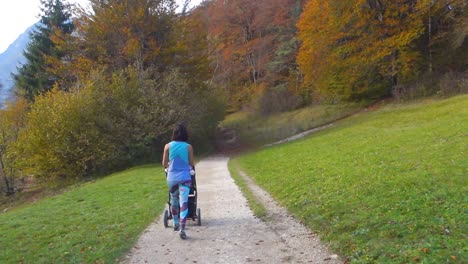 Young-mother-pushing-baby-stroller-on-a-dirt-road-by-the-Bohinj-Lake,-Slovenia