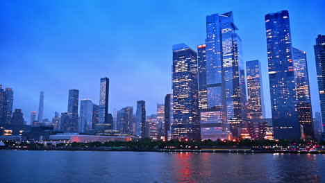 stunning beautiful modern high-rise architecture of modern new york with lights on in the windows. low angle view from the river at dusk time
