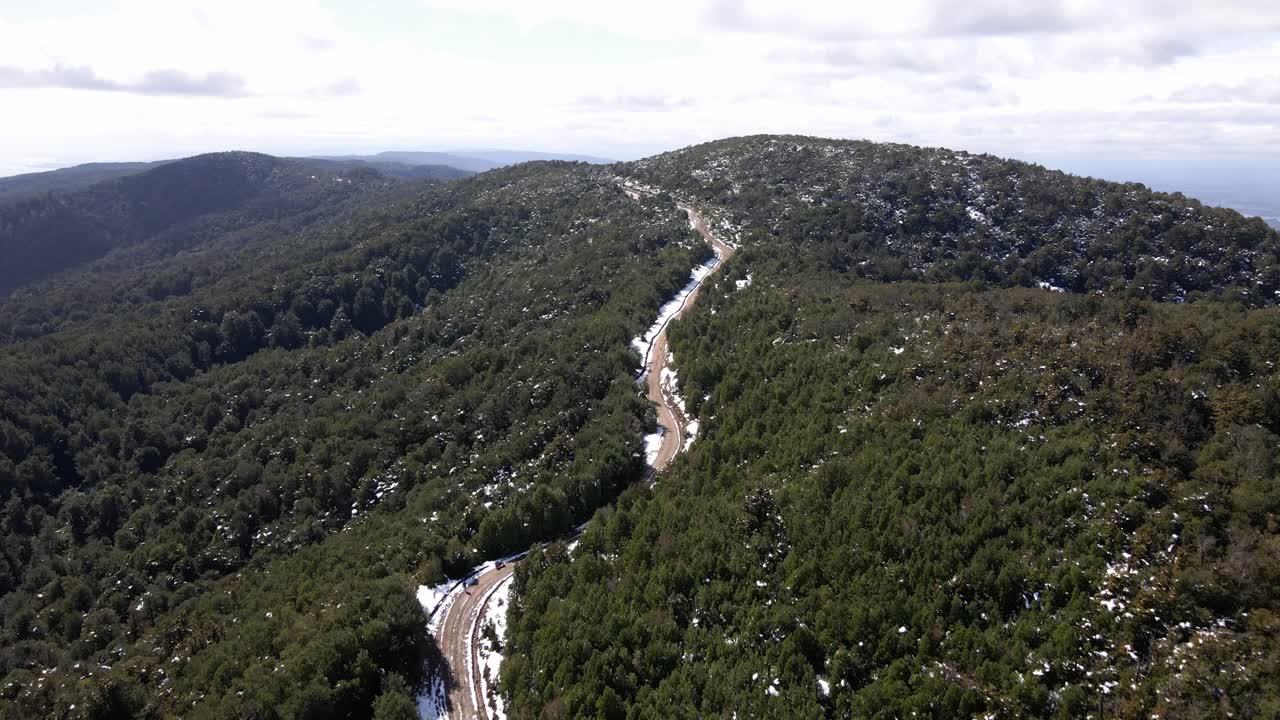 Tomada aérea com aproximação de estrada de terra com neve no Parque Oncol, Chile.