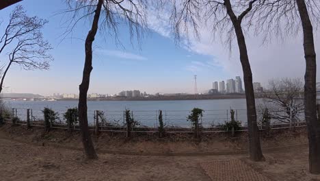 seonyudo park, seoul - empty swing bench swinging with view of han river and city skyline in distance. wide pullback shot