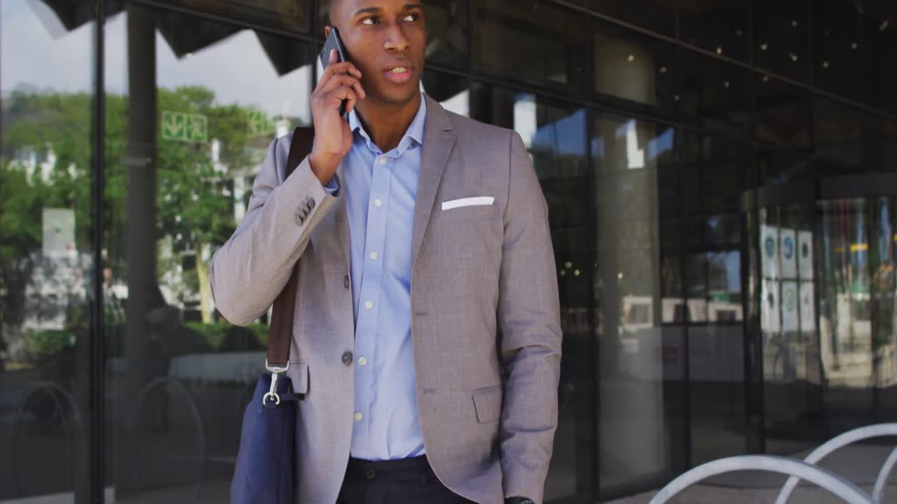 African american businessman talking on smartphone outside of modern office building