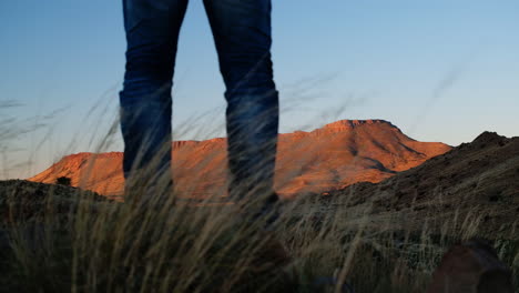 Man-stands-at-lookout-point-with-scenic-view-of-Karoo-mountain-at-sunset