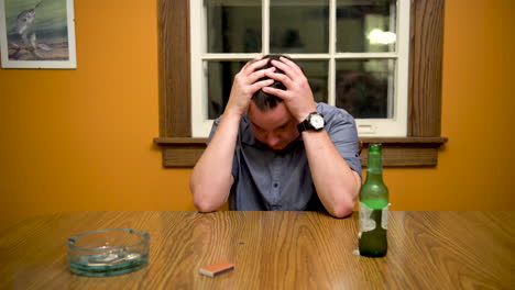 hombre estresado en la mesa bebiendo, pasando las manos por el cabello