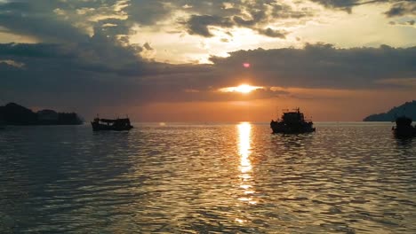 Toma-En-Cámara-Lenta-De-La-Puesta-De-Sol-Sobre-Los-Barcos-En-Una-Bahía-En-Borneo,-Malasia