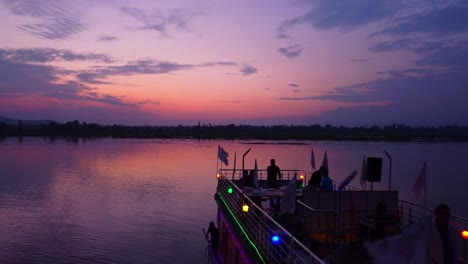luxury cruise with tourists on small island in dal lake of kashmir at sunset twilight, jammu and kashmir, drone shot