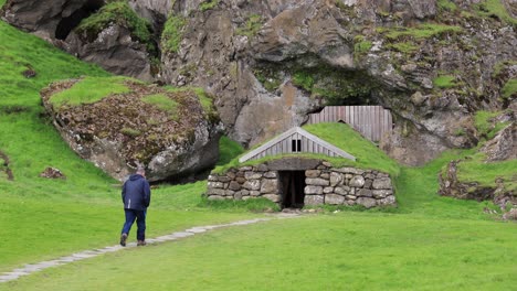 man walking towards stone hut in iceland 4k