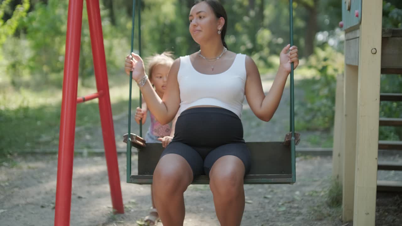 madre y hija embarazadas jugando en el columpio al aire libre