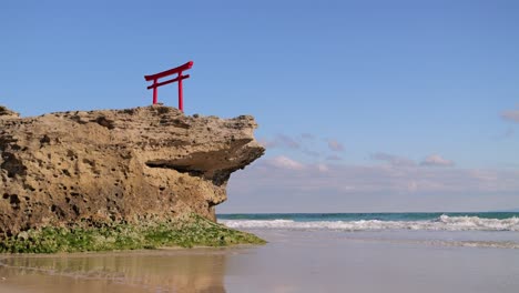 calm minimalist scenery at ocean with japanese torii gate on top of rock cliff