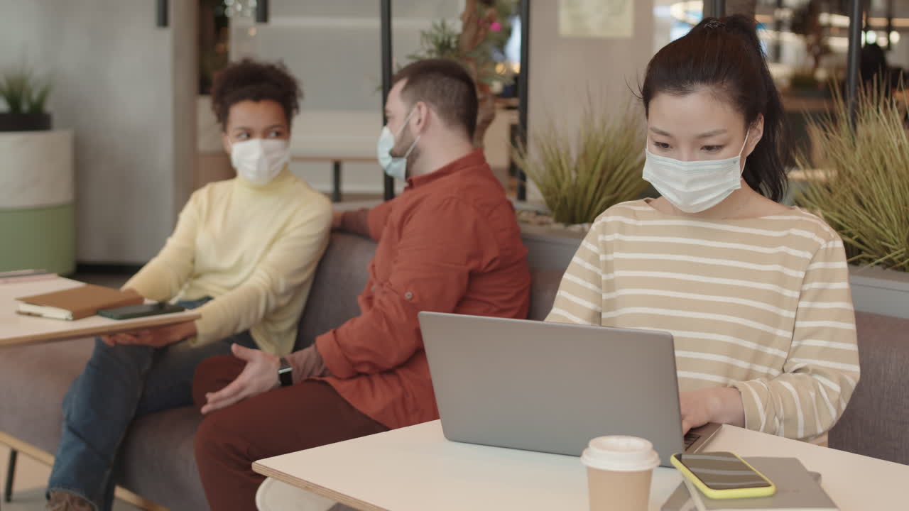 Woman in Mask Using Computer in Cafe