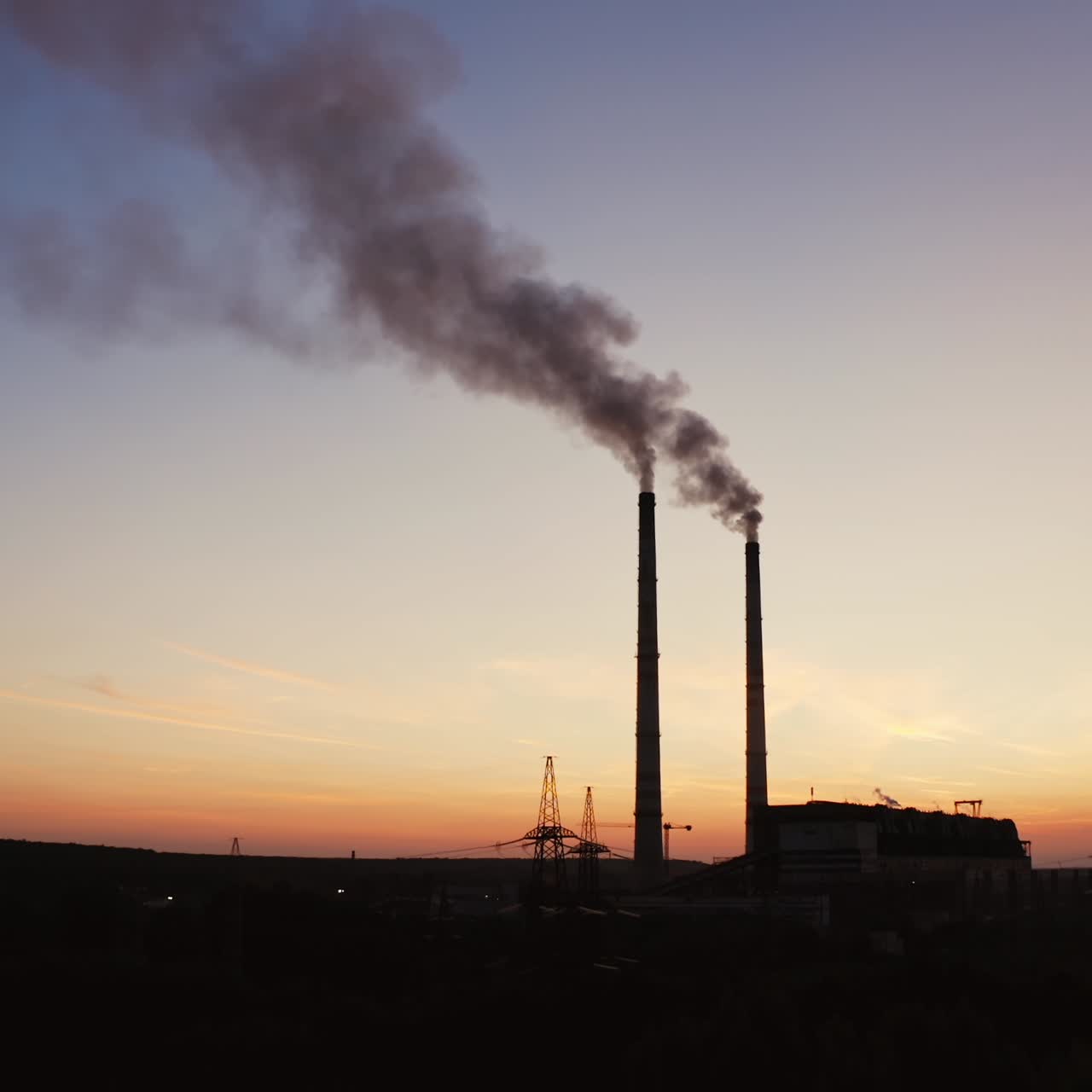Dark background of plant with industrial pipes. Smokestacks of the plant against the background of an orange sunset. Bad ecological situation. Air pollution.