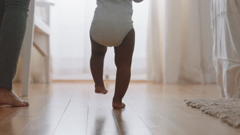 El-Bebé-Aprende-A-Caminar.-El-Niño-Pequeño-Da-Los-Primeros-Pasos-Con-La-Madre-Ayudando-Al-Bebé-A-Enseñarle-Al-Niño-En-Casa.