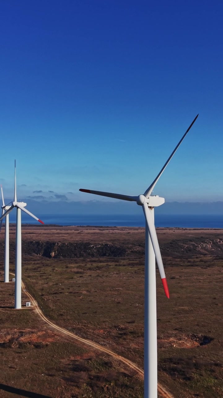 Aerogeneratori si ergono alti contro un cielo blu vicino alla costa