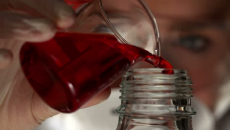 Scientist-pouring-red-liquid-into-bottle