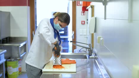 kitchen employee with face mask prepares vegetables