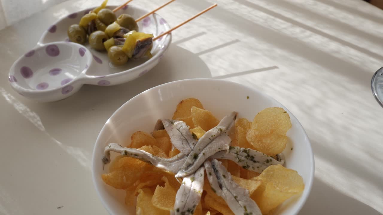 Delicious tapas with vermouth served on a cozy table, featuring chips, olives, and anchovies