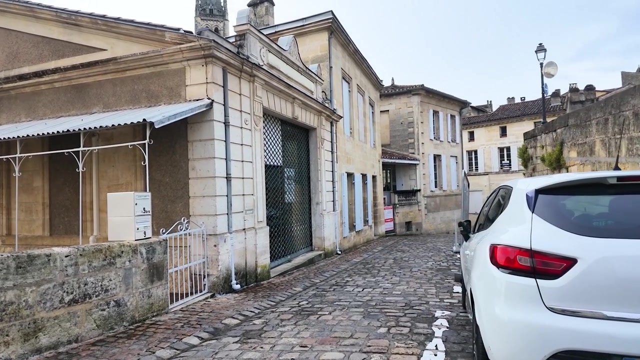 A slow camera pan moves through a historic French village street with limestone buildings