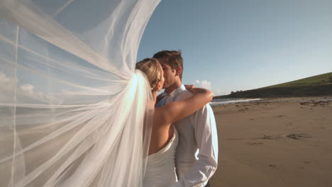 Kissing-bridal-couple-standing-on-the-beach