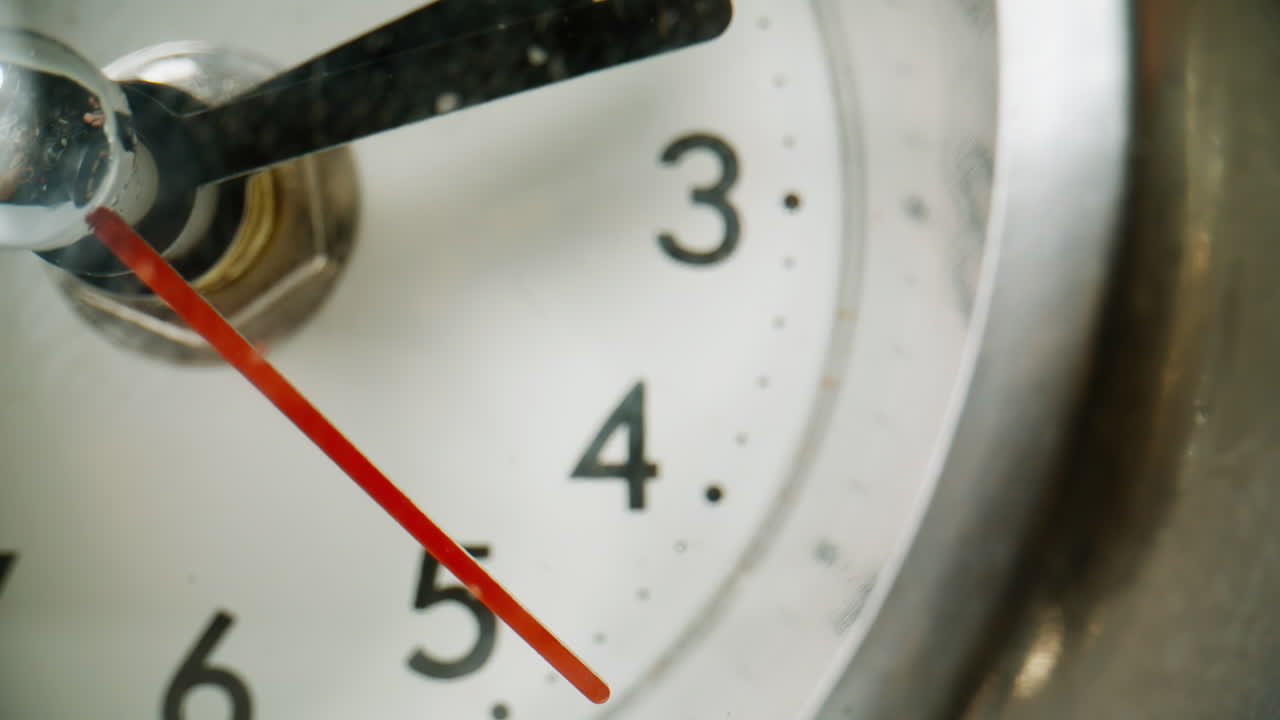 Macro seconds hand ticking on white background retro clock. Closeup red arrow