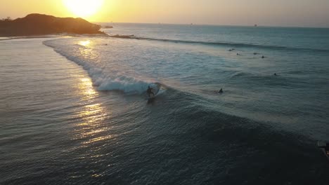 drone aerial view following a pro surfer, during sunset, at the coast of talara, in peru - tracking, drone shot