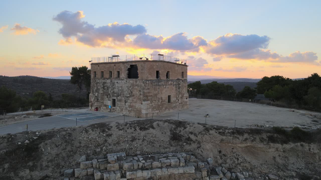 Drone captures expansive aerial footage of ancient stone building at dusk in British Columbia, Canada. Dramatic sky with colorful clouds enhances the historic, rugged ambiance