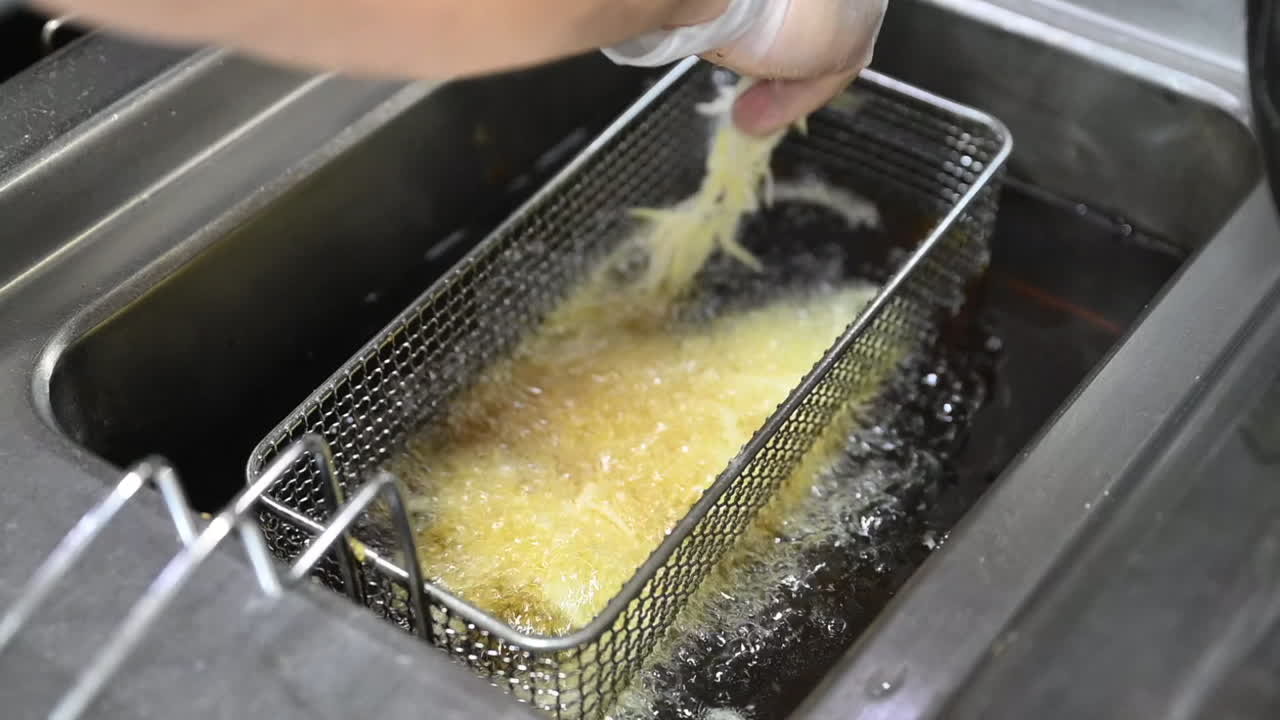 Stegning af tynde kartoffelskiver i en automatisk friturekoger, tilberedning af tyrkisk kebab.