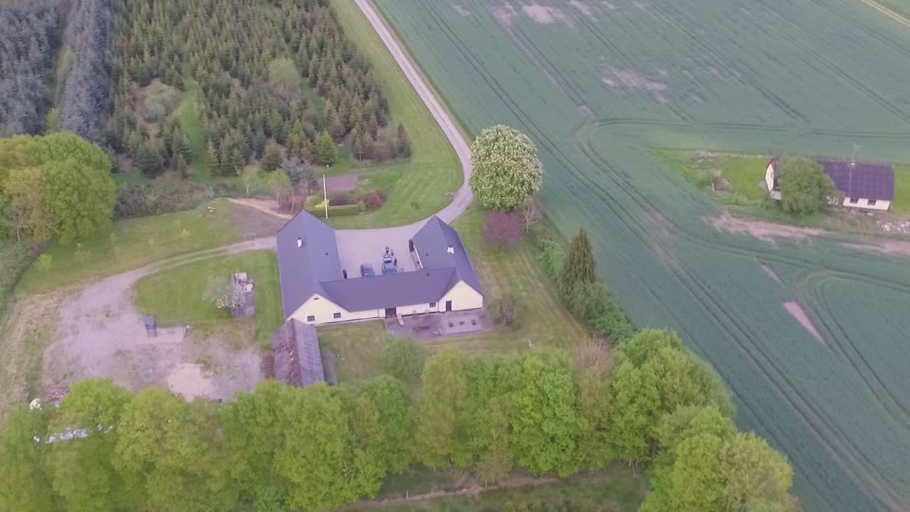Ilmakuvaus hitaasti lähestyvästä maatilasta, jossa on paljon vihreitä puita ja kasveja.