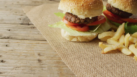 video of two burgers and chips on sackcloth and wooden table