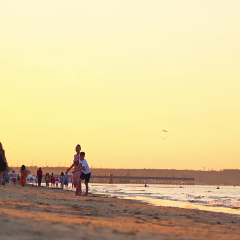 joyful woman with a boy spending a good time at seaside. happy mother is running together with her son on the seashore in the evening. summer vacation.