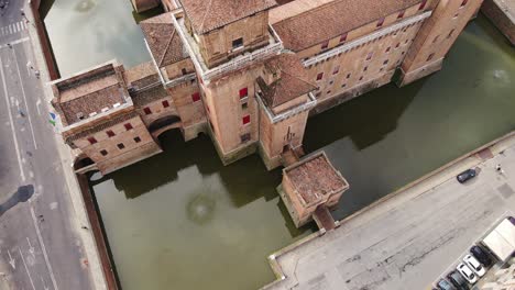 Drone rises above Ferrara’s water-surrounded castle in old town panorama, Italy