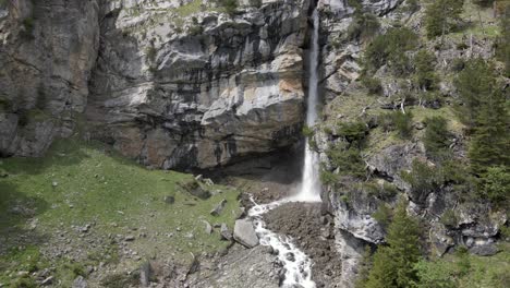 antena que revela una cascada que se derrumba detrás de una roca maciza creando una neblina de agua salpicada