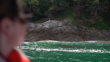 Sailing-along-the-coast-with-amazing-views-of-the-shoreline-and-clear-green-ocean-water-in-slow-motion