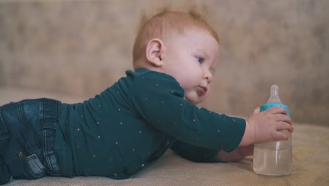 girl hugs little brother nibbling rubber teat on large bed