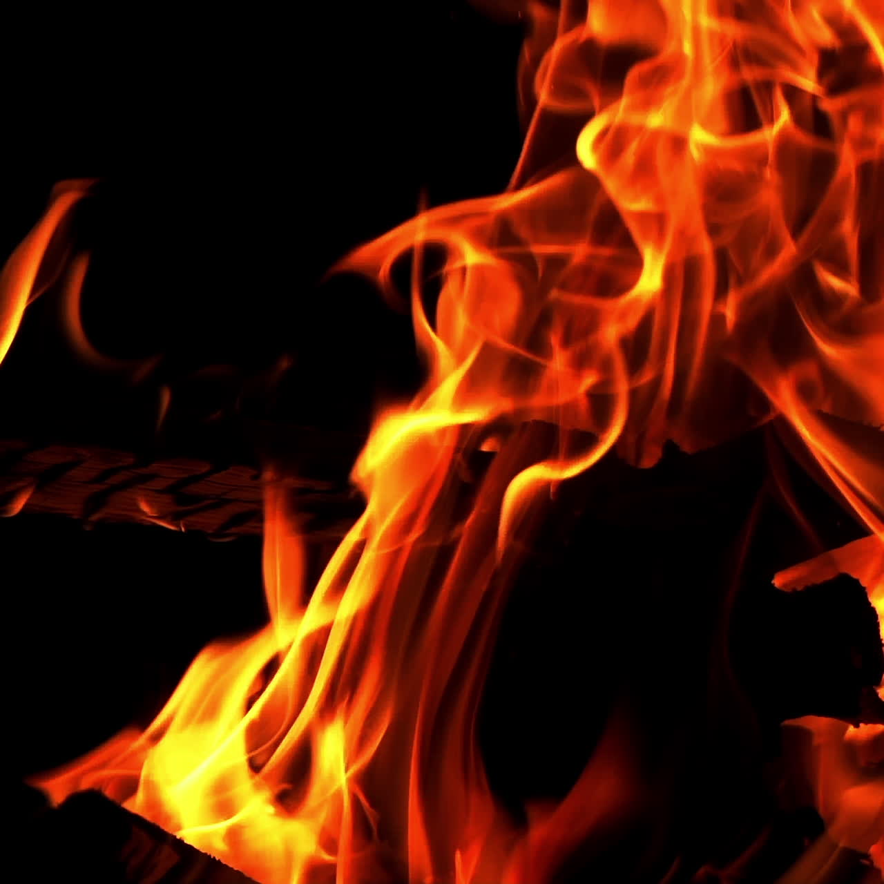Movimento dettagliato di un bellissimo falò che arde vivacemente su sfondo nero. Ceppi che bruciano nel falò con una fiamma arancione. Primo piano