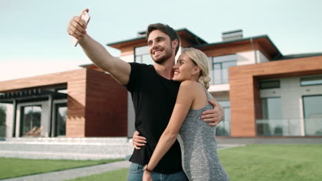 pareja rica abrazándose cerca de apartamentos de lujo. retrato selfie de pareja feliz