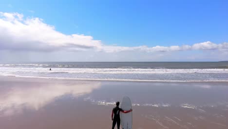 Male-surfer-standing-with-surfboard-at-beach-on-a-sunny-day-4k