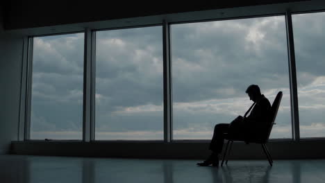 man sitting by a window on a cloudy day