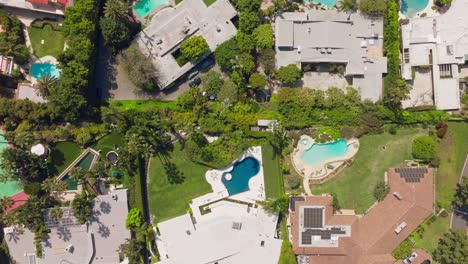 drones volando sobre las fincas de beverly hills, casas de lujo con piscinas brillantes en un día soleado