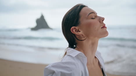 woman enjoy breeze standing near waves close up. model posing seashore vertical