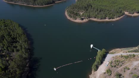 Aerial-forward-tilt-up-reveal-over-Penha-Garcia-dam-and-panorama-in-background,-Portugal