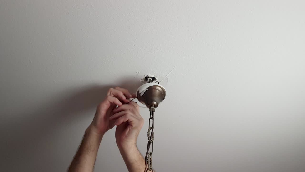 quitando la cinta aislante de algunos cables que están conectados a una luz de techo