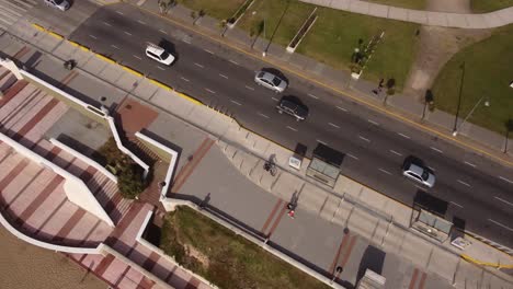 hermosa vista de arriba hacia abajo de un ciclista en la calle de mar del plata en argentina en un día soleado con autos moviéndose por la carretera