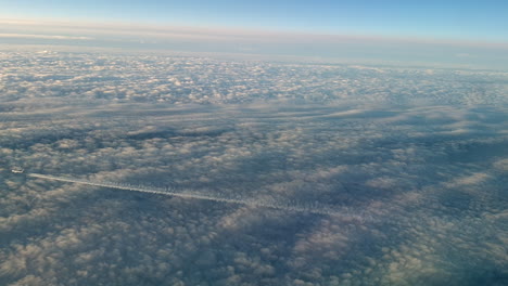 Incredible-view-from-the-cockpit-of-an-airplane-flying-high-above-the-clouds-leaving-a-long-white-condensation-vapour-air-trail-in-the-blue-sky