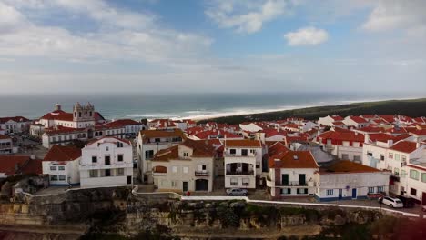 aerial view of iconic nazare red roofed buildings overlooking atlantic ocean