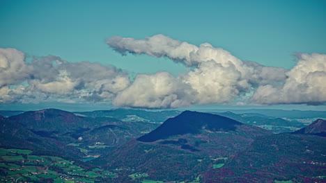 nubes blancas esponjosas rodan y se curvan en el cielo sobre los escarpados picos de las montañas en el campo